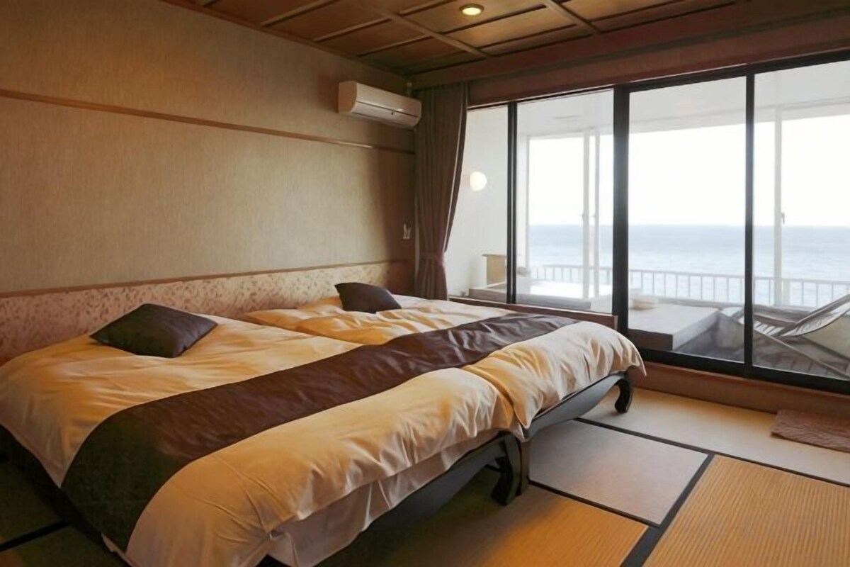 Una habitación con cama, vistas al mar y balcón.