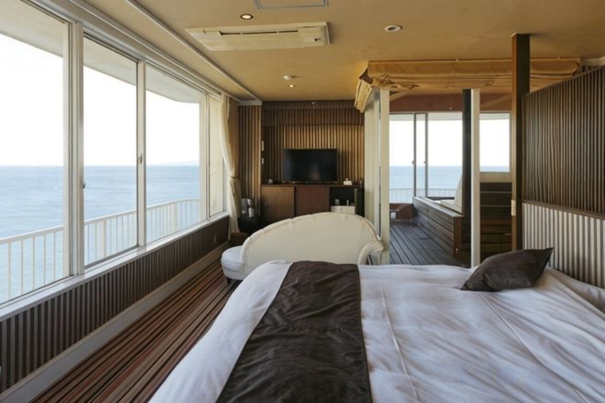 Ein Schlafzimmer mit einem großen Bett, einem Fernseher und Meerblick.