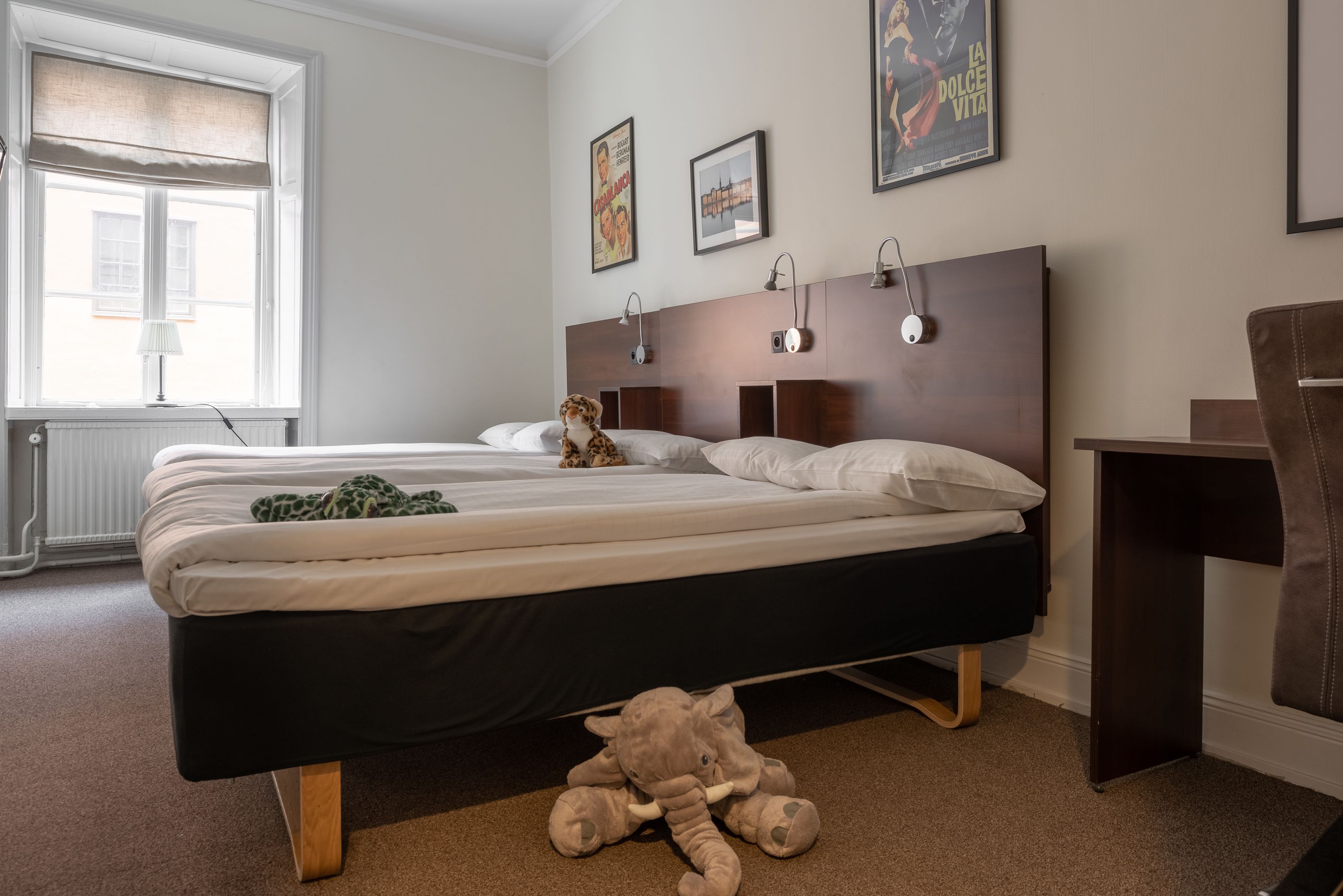 Una camera da letto con un letto, una scrivania e un peluche sul pavimento.