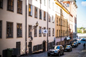 A cobblestone street lined with historic buildings, parked cars, and a bicycle.
