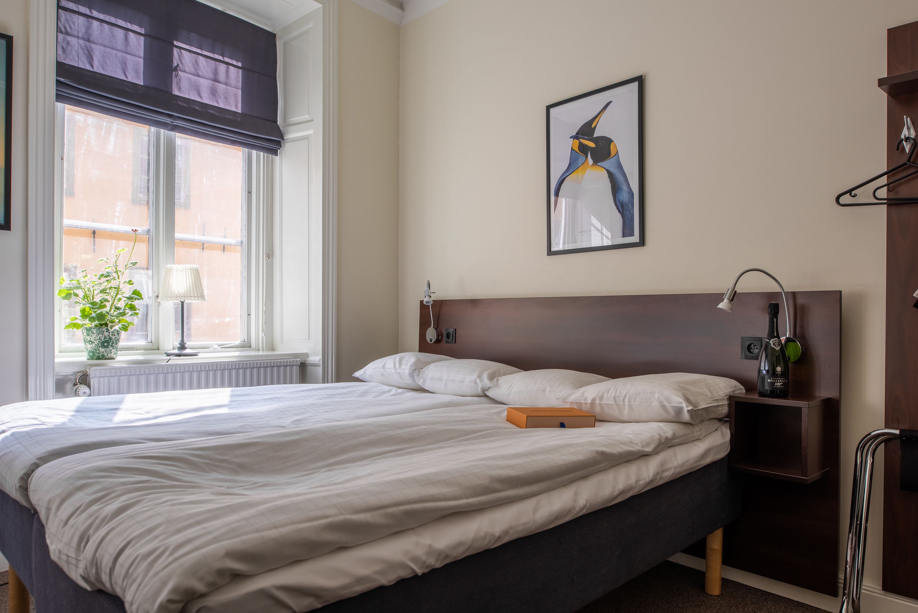 A neatly made bed with white linens, a dark headboard, and a framed artwork above it.