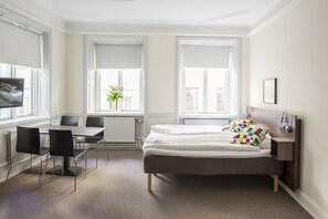 A modern bedroom with a bed, bedside table, and a desk with chairs.