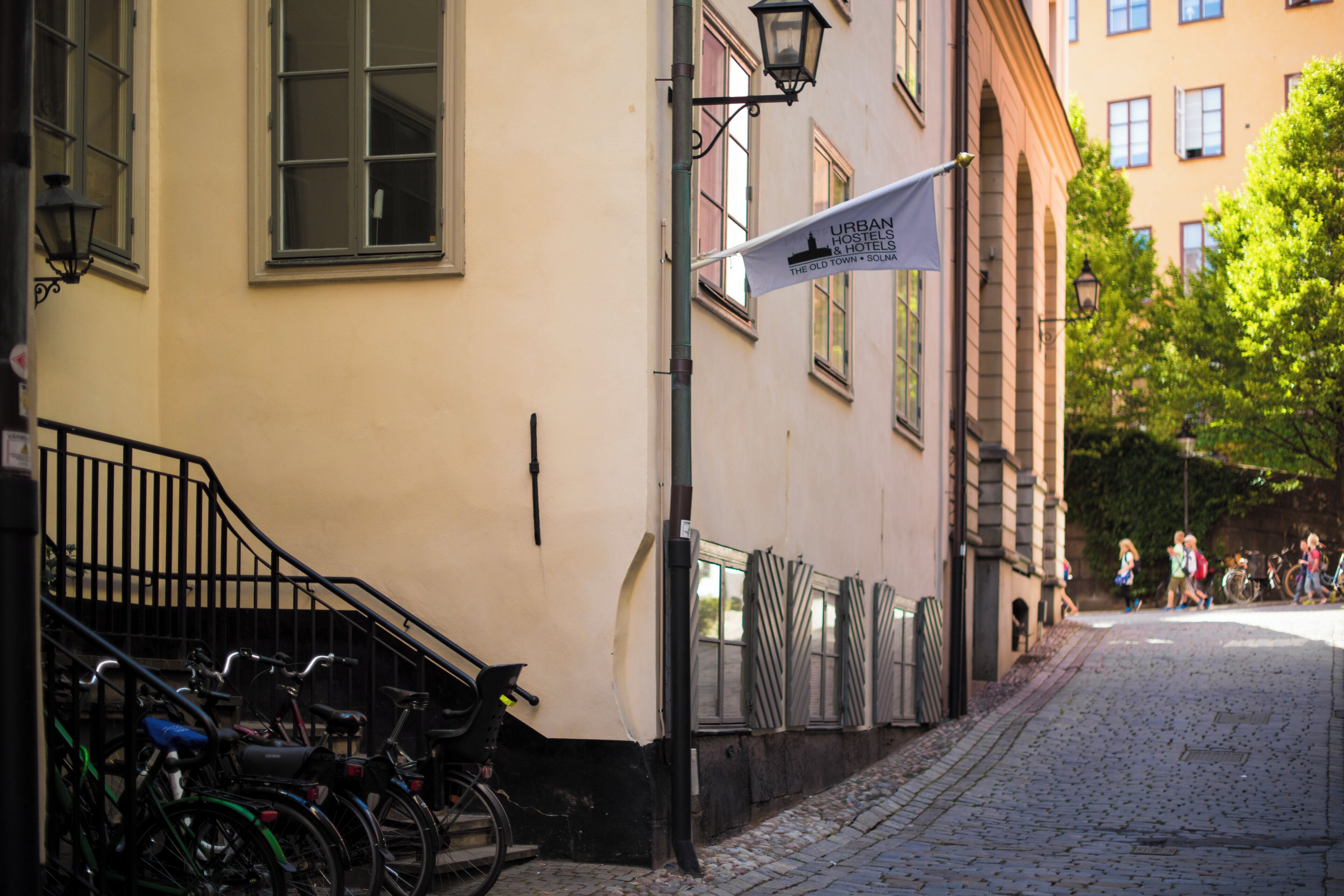 Une rue pavée où sont garés des vélos contre un immeuble sur lequel est accrochée une banderole faisant la publicité d’auberges de jeunesse et d’hôtels en ville.