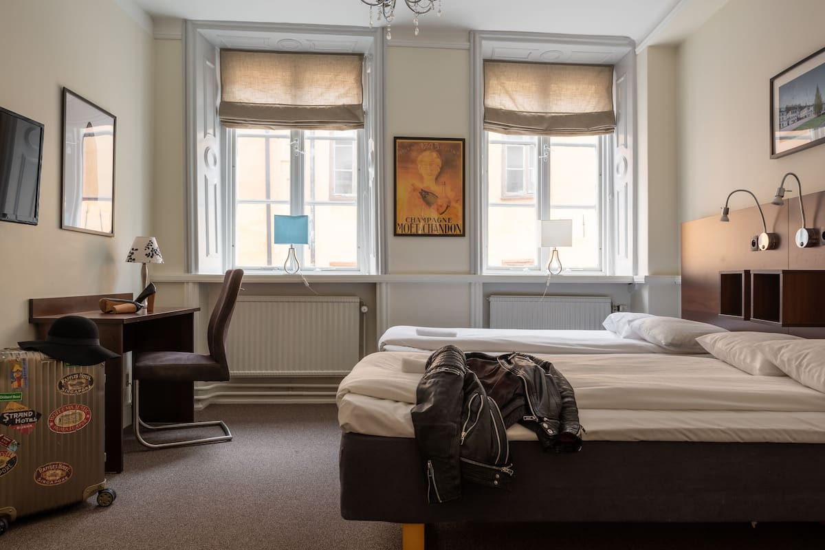 Habitación de hotel con cama, escritorio, silla y radiador.