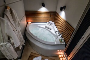 A modern bathroom with a freestanding bathtub, wooden paneling, and a towel rack with robes. - Discovery Hotel (Istanbul)