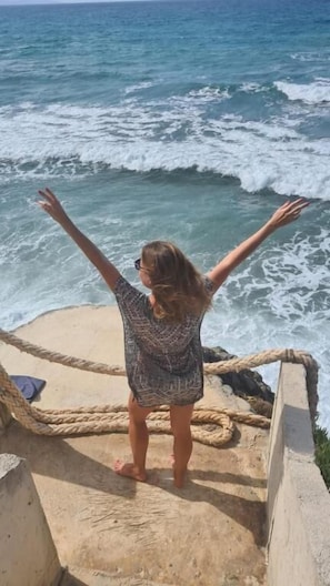 A person standing on a concrete platform with a rope barrier, overlooking the ocean. - Sun Camero Apartments (Pomos)