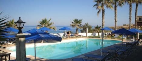 Una piscina al aire libre de temporada, sombrillas