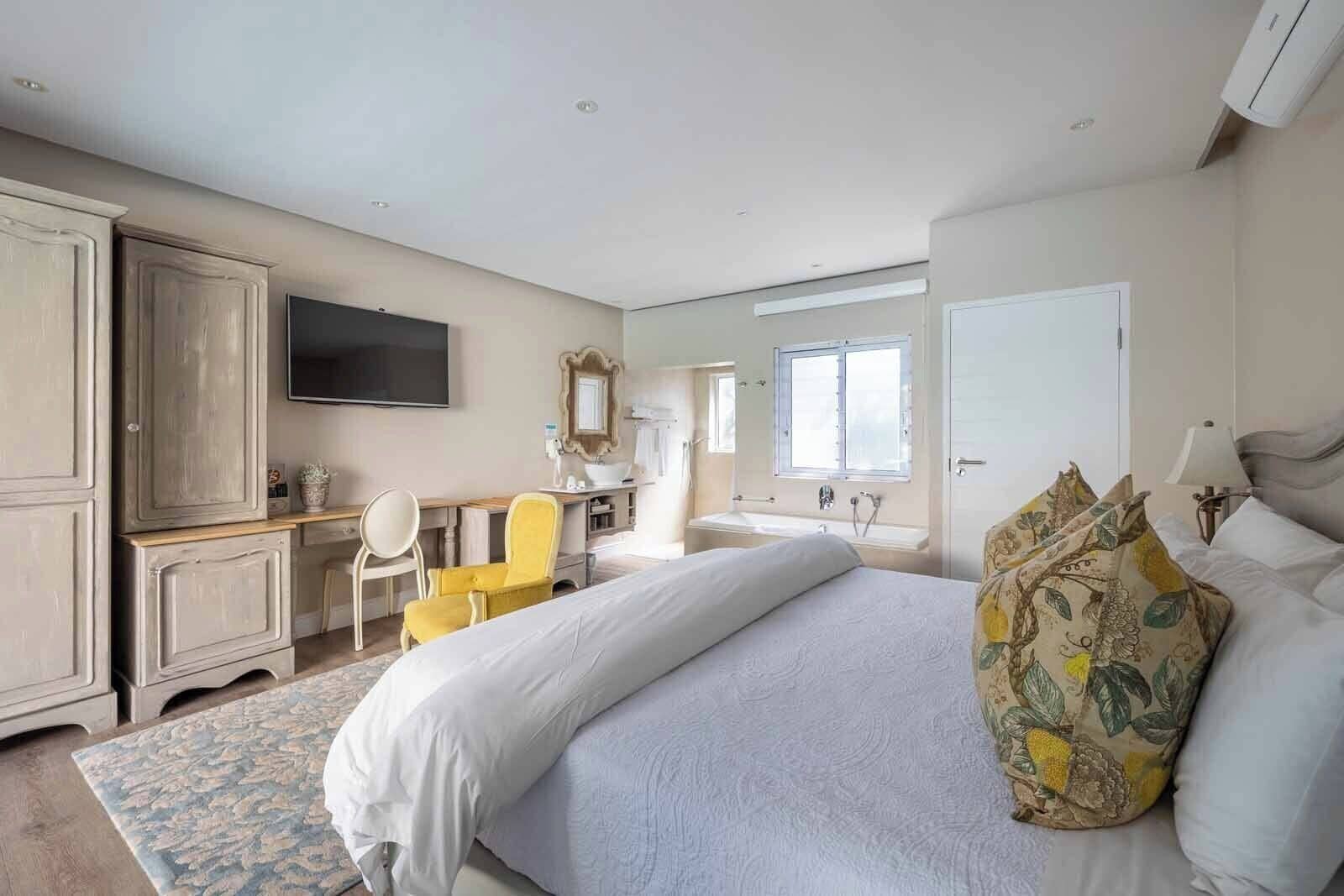 A bedroom with a bed, a desk, a chair, a wardrobe, a television, and a bathroom.