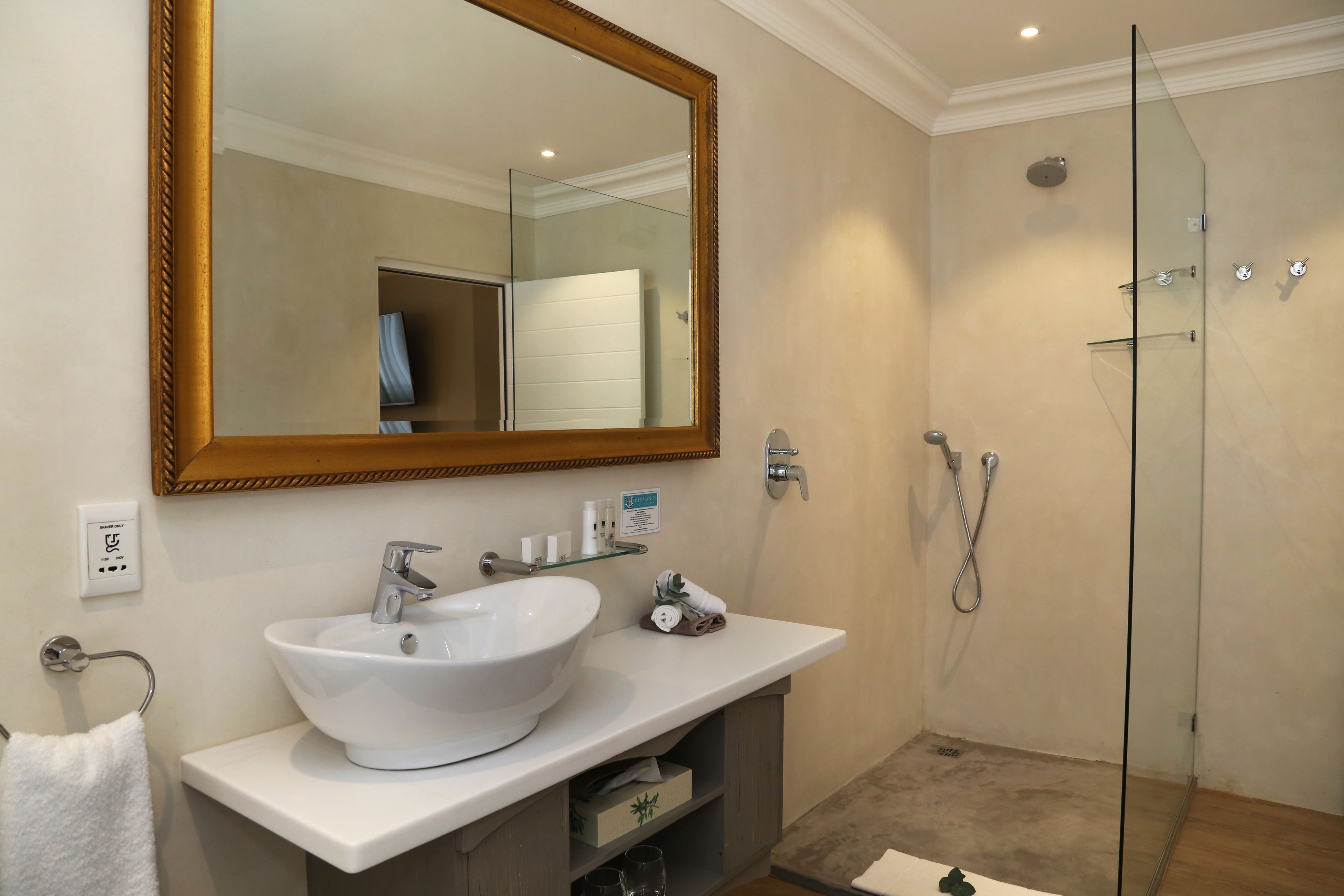 A bathroom with a white sink, a large mirror, and a glass-enclosed shower.