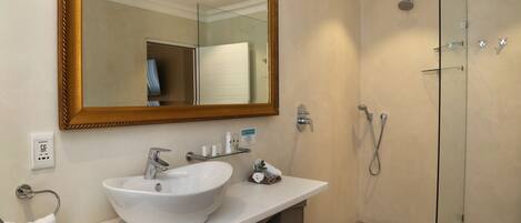 A bathroom with a white sink, a large mirror, and a glass-enclosed shower.