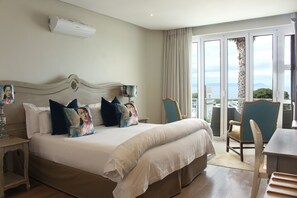 Relax in comfort with a large bed, featuring a decorative headboard and plush pillows, and enjoy the view from the balcony.