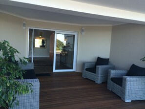 Relax in a serene space with a sofa and armchairs, surrounded by a clean design and a door leading to an outdoor area.