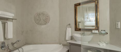 A bathroom with a bathtub, a sink, a mirror, and a towel rack.