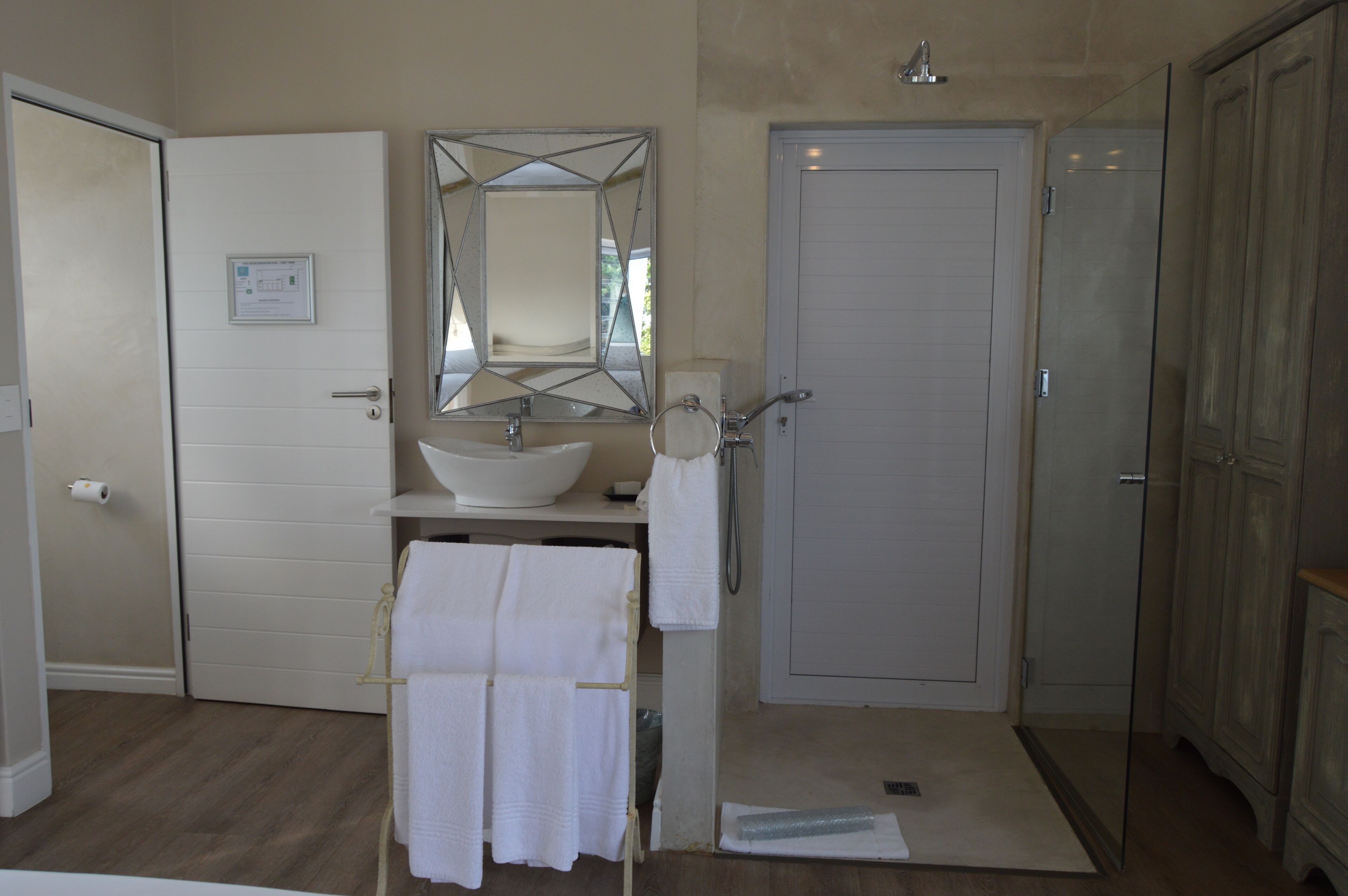 A bathroom with a white sink, a mirror, a towel rack, and a shower area.