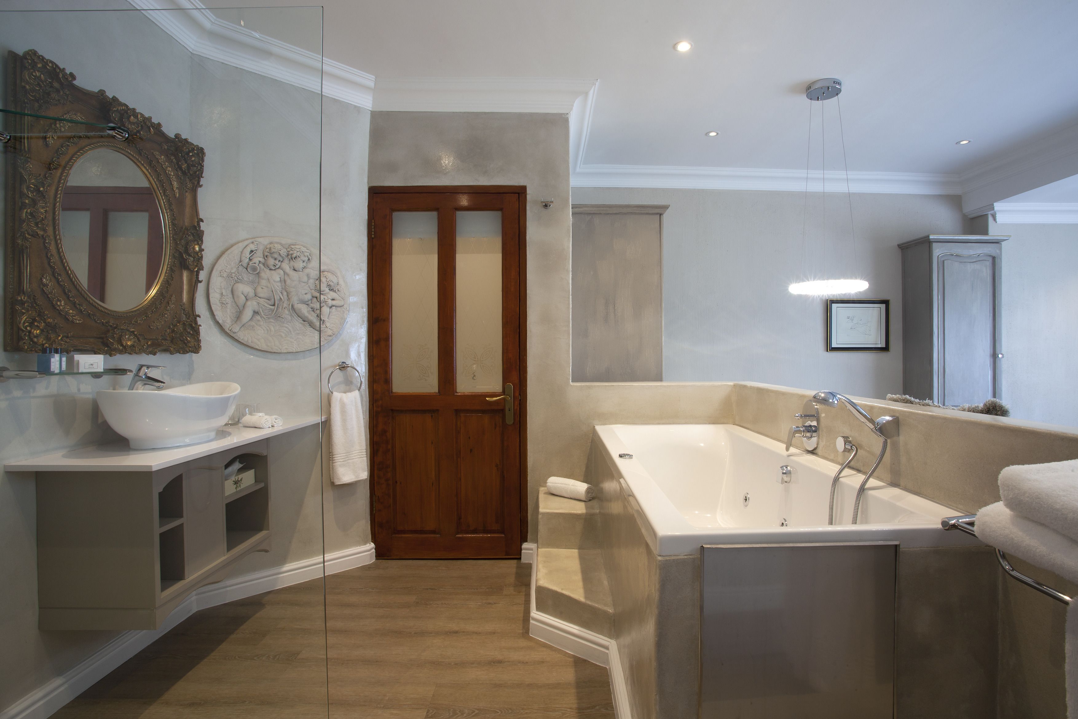 Un baño moderno con una bañera independiente, un espejo grande y una puerta de madera.