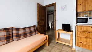 A room with a wooden sofa, a television on a wooden stand, and a microwave on a wooden cabinet. - Residence Gardenia (Livigno)