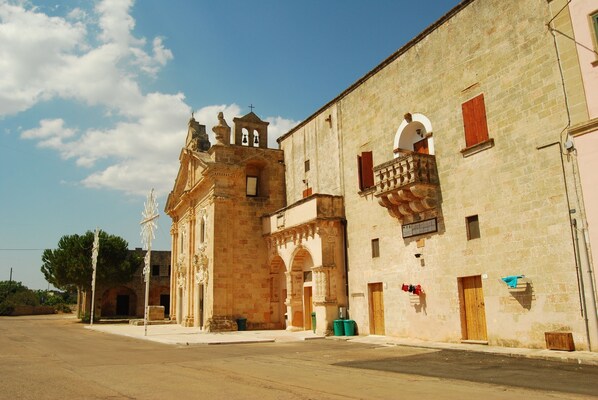 A historic building with a bell tower, arched doorways, and a balcony with a railing. - Terra di Leuca (Salve)