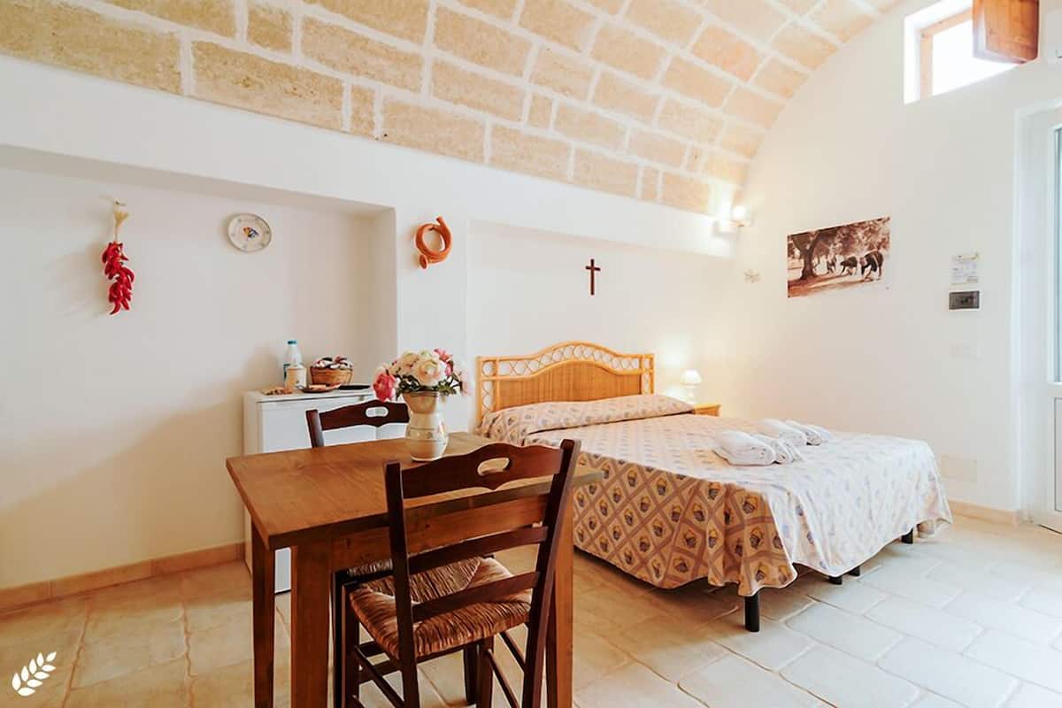 Um quarto aconchegante com uma cama de madeira, uma pequena escrivaninha e uma mesa de jantar.
