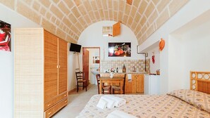 Un dormitorio con una cama, un armario de madera, un escritorio y una kitchenette.