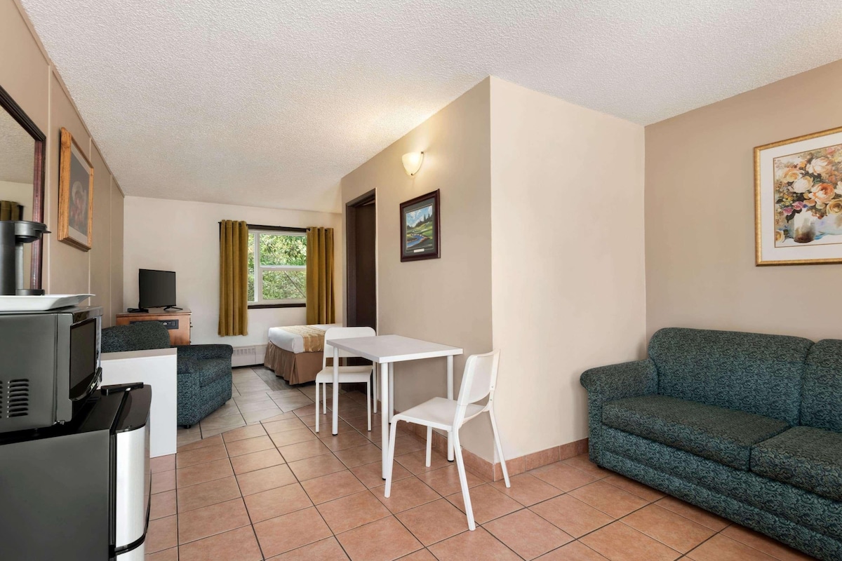 Un espace de vie compact comprenant un coin cuisine, un coin repas avec une table et des chaises, un canapé et un téléviseur.