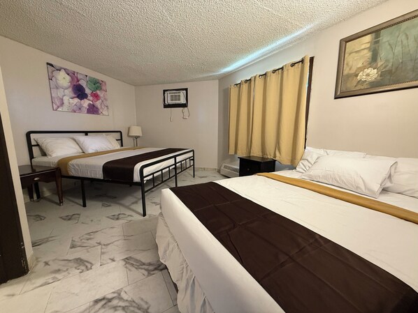 Une chambre d’hôtel avec deux lits simples, un sol en marbre, un ventilateur de plafond, un tableau et une fenêtre avec des rideaux.