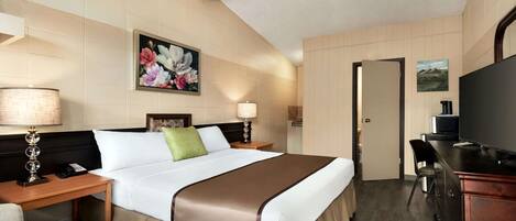 Habitació d'hotel amb un llit, taules de nit, una televisió i un escriptori.