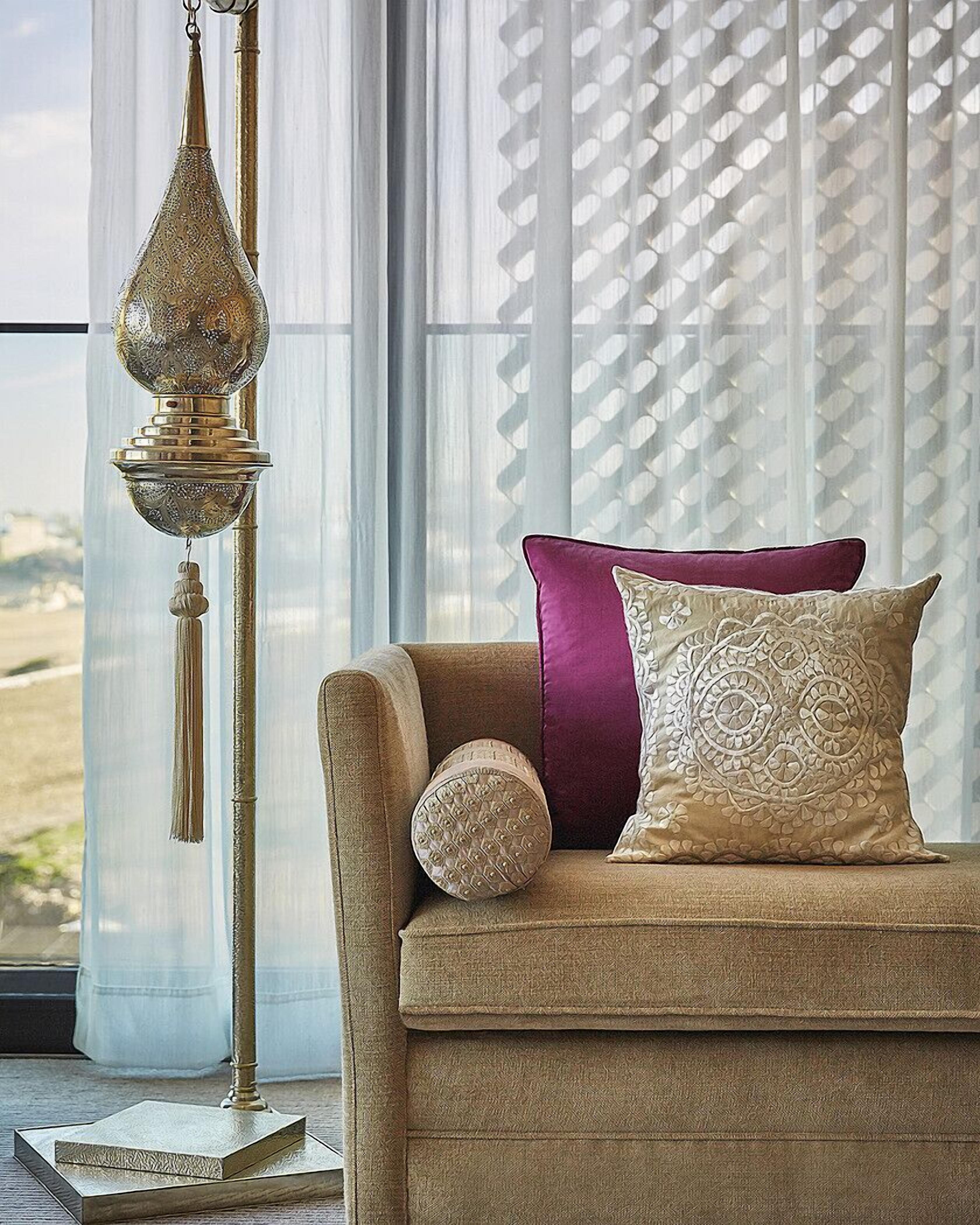 A living room with a sofa, a decorative lamp, and a view through sheer curtains.