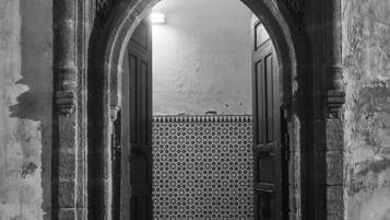 An arched doorway with intricate carvings, leading to a tiled room.