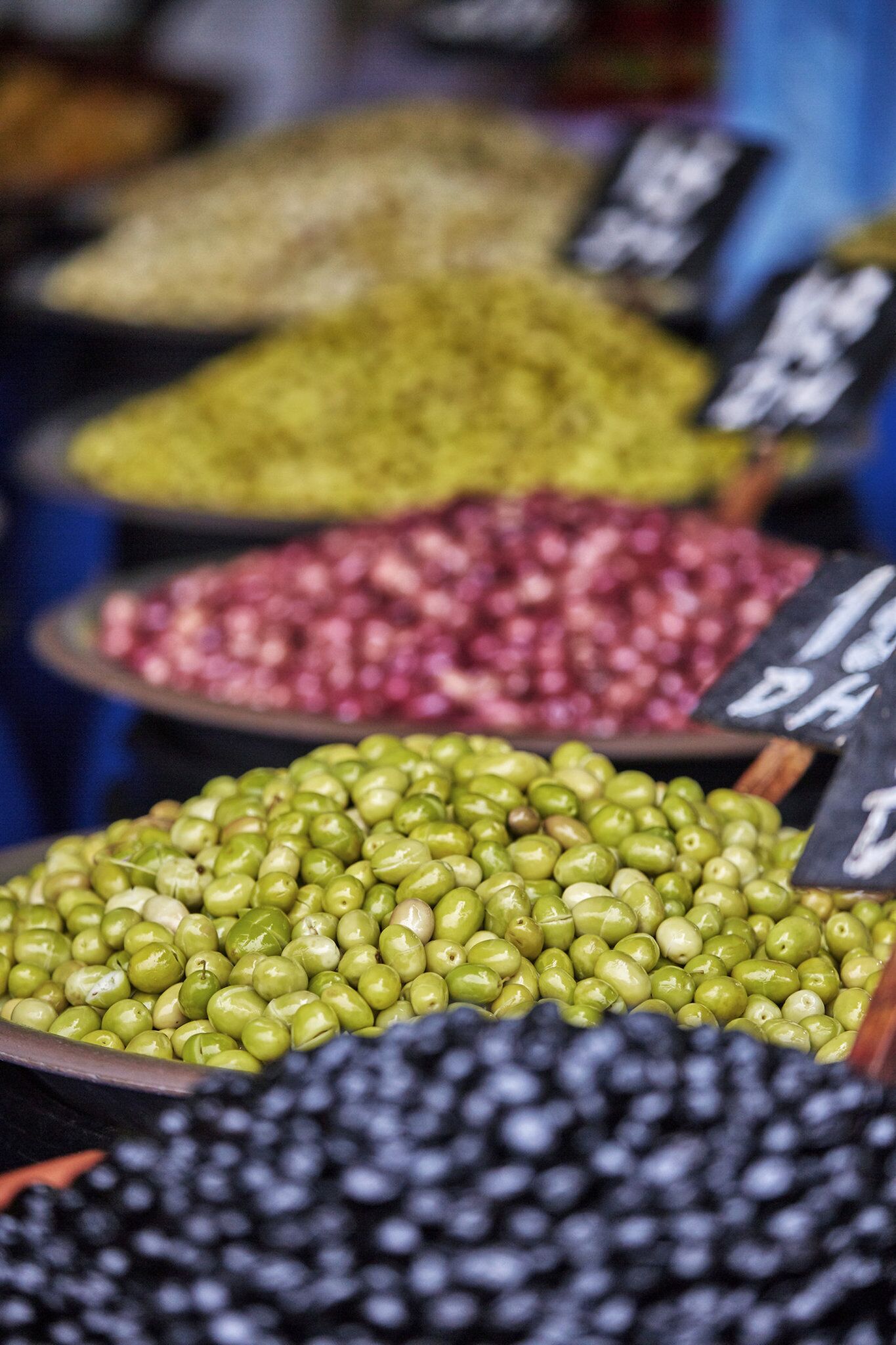 Un puesto de mercado con distintos tipos de aceitunas expuestas en cuencos.