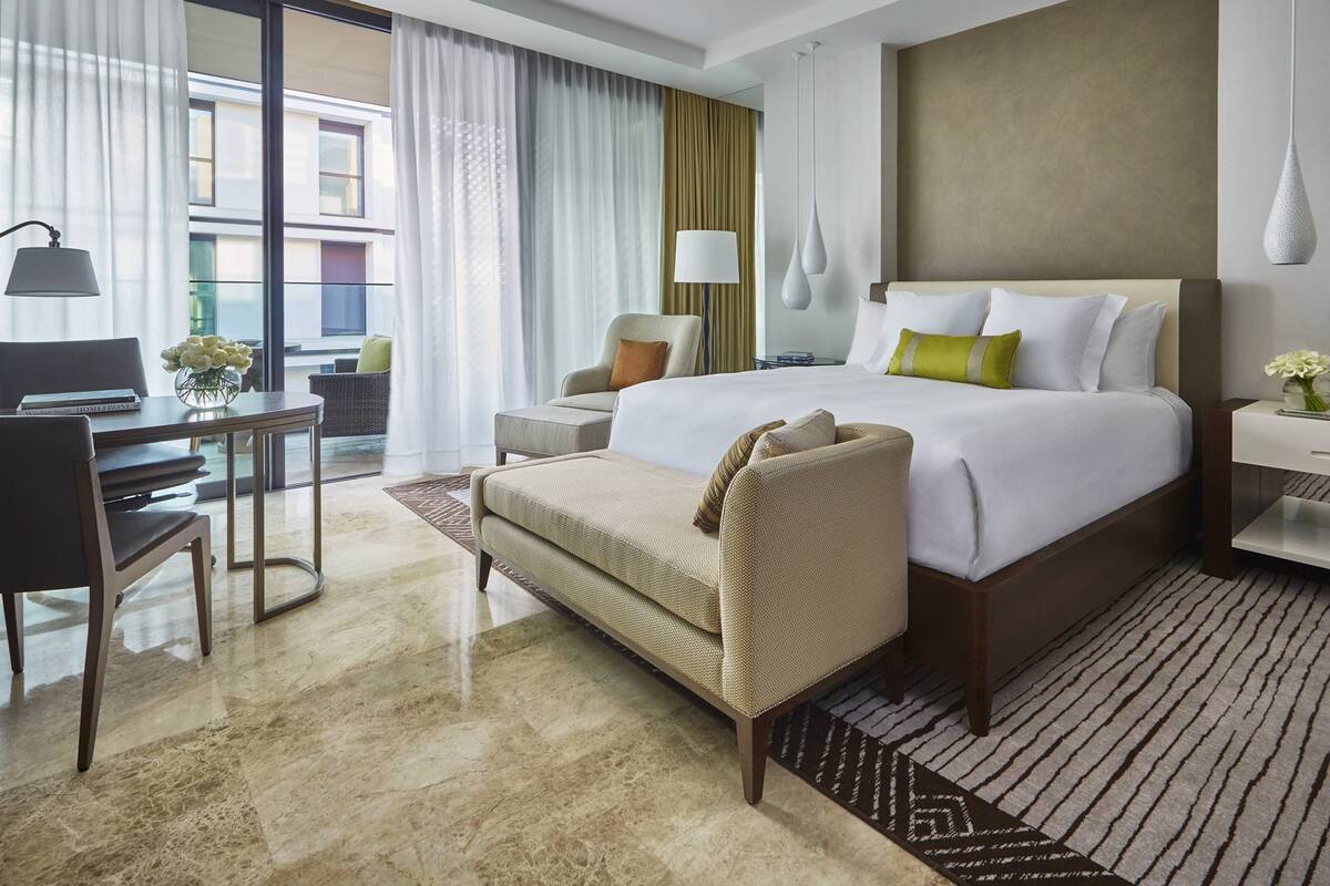 A hotel room with a bed, a desk, a chair, and a sofa.