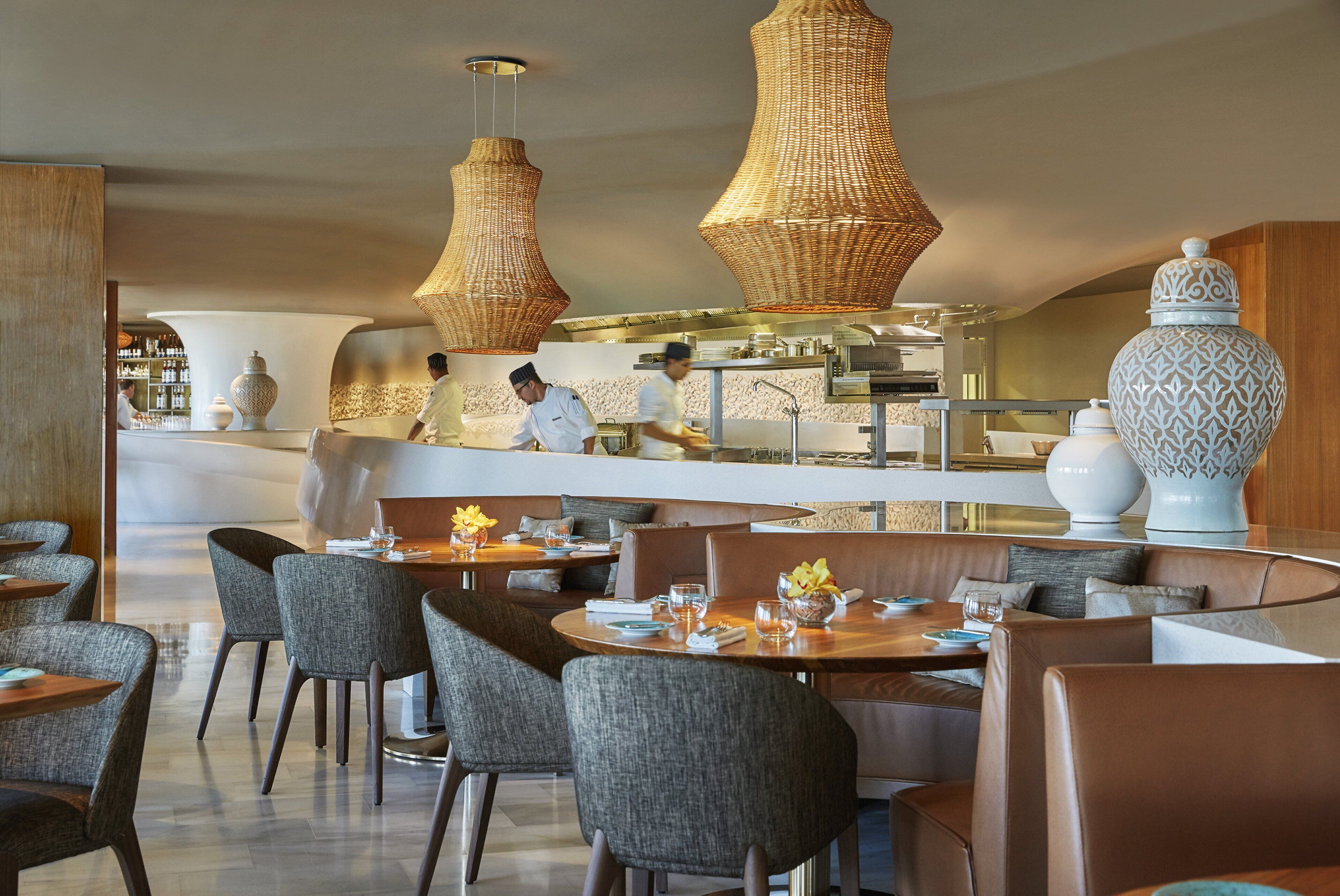 En restaurang med höga bord, stoppade stolar och hängande lampor av rotting.