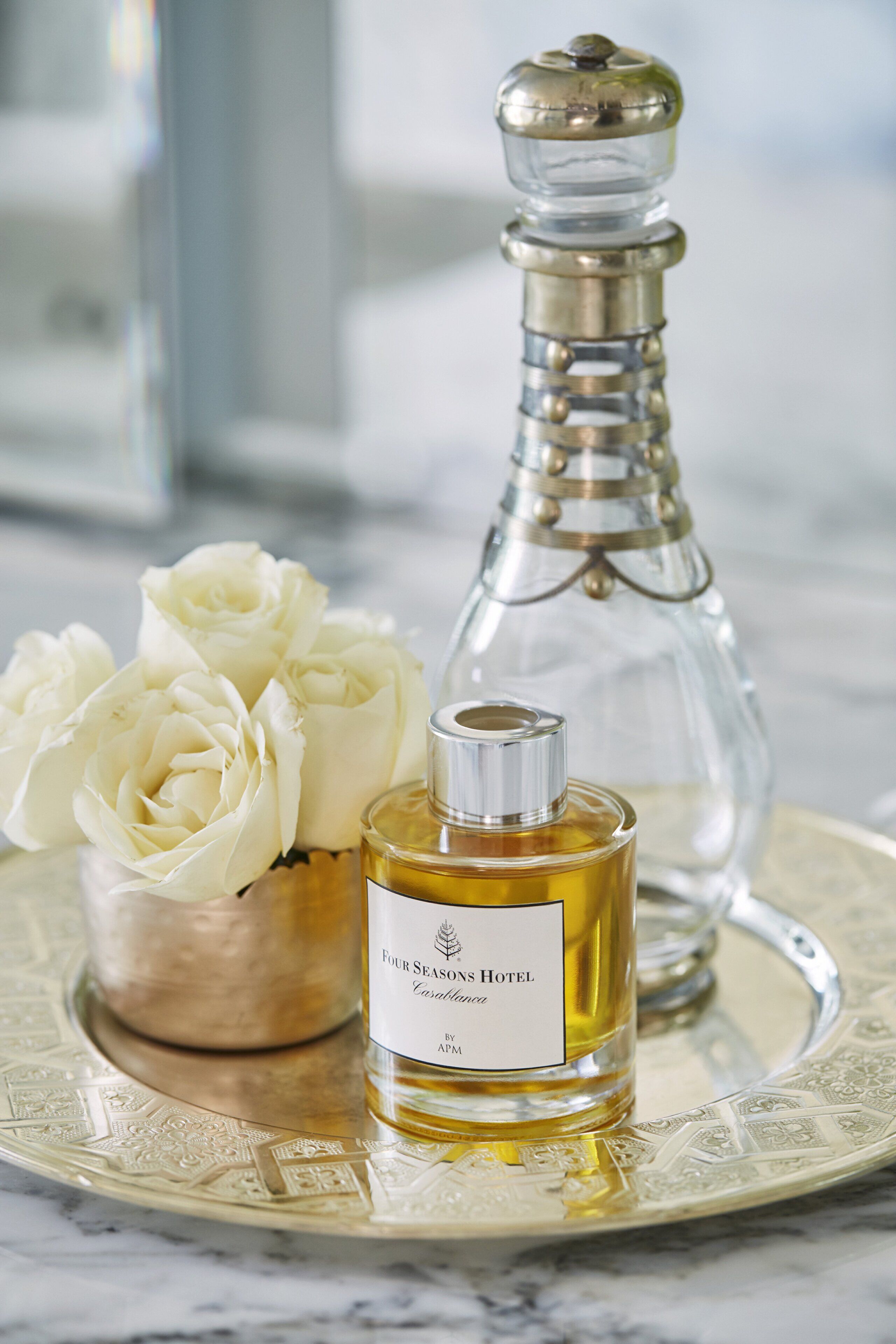 Una botella de perfume jazmín del Hotel Four Seasons, un salero y rosas blancas sobre una bandeja.
