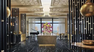 Experience the grandeur of our lobby, featuring a grand piano, elegant vase, and stunning ocean views through large windows.