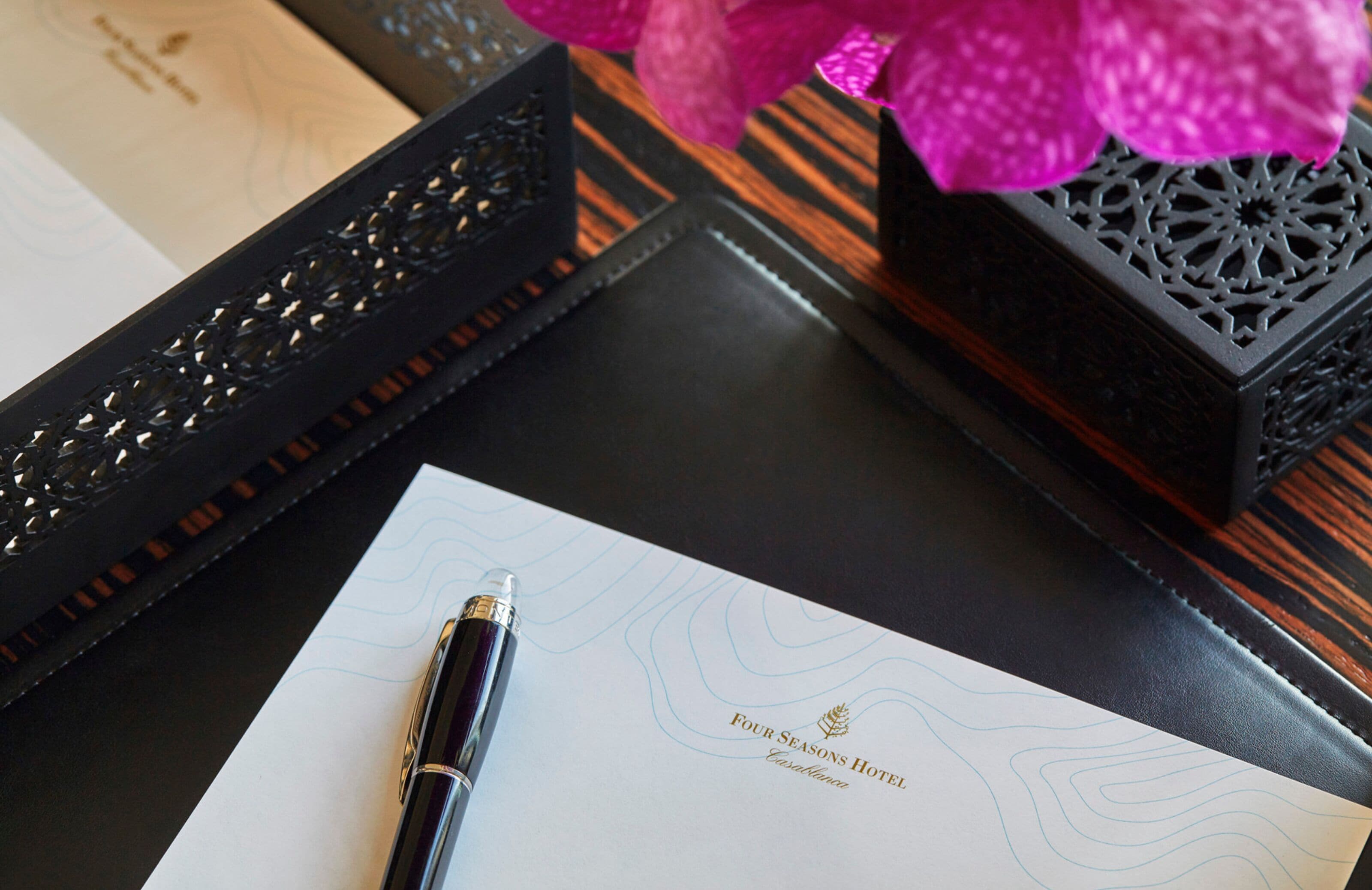 A hotel room with a black tray table, a pen, and a paper with the hotel name.
