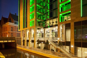 A modern hotel with a glass facade, multiple floors, and a central staircase. - Holiday Inn Manchester - City Centre by IHG (Manchester)