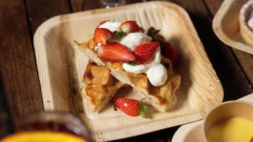 Een vierkant houten bord met een dessert, versierd met aardbeien en slagroom.