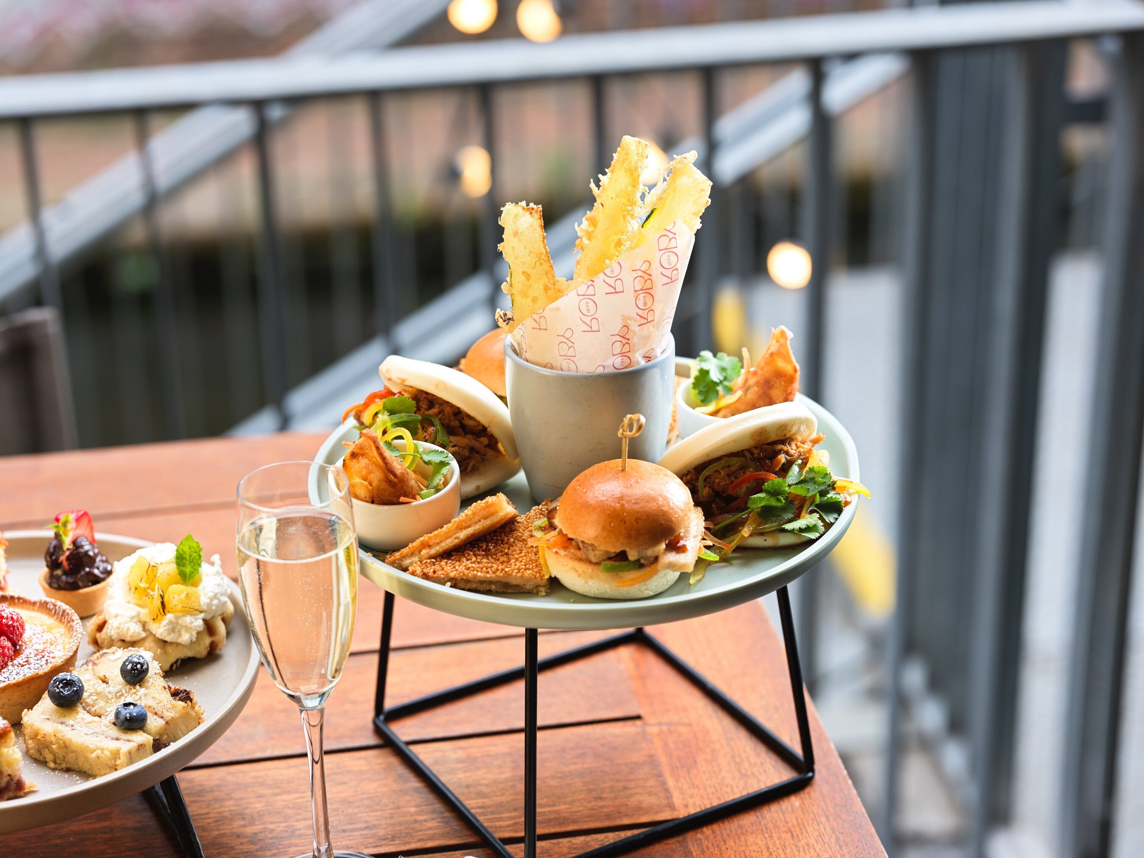 A dining table with a variety of food items, including sandwiches, a glass of water, and a dessert plate.
