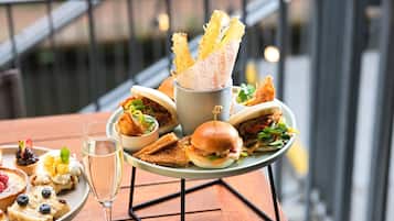 A dining table with a variety of food items, including sandwiches, a glass of water, and a dessert plate.