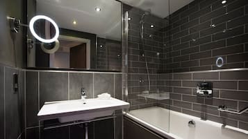 Un bany modern amb dutxa tancada amb vidre, un lavabo blanc i un mirall amb llum d'anell.