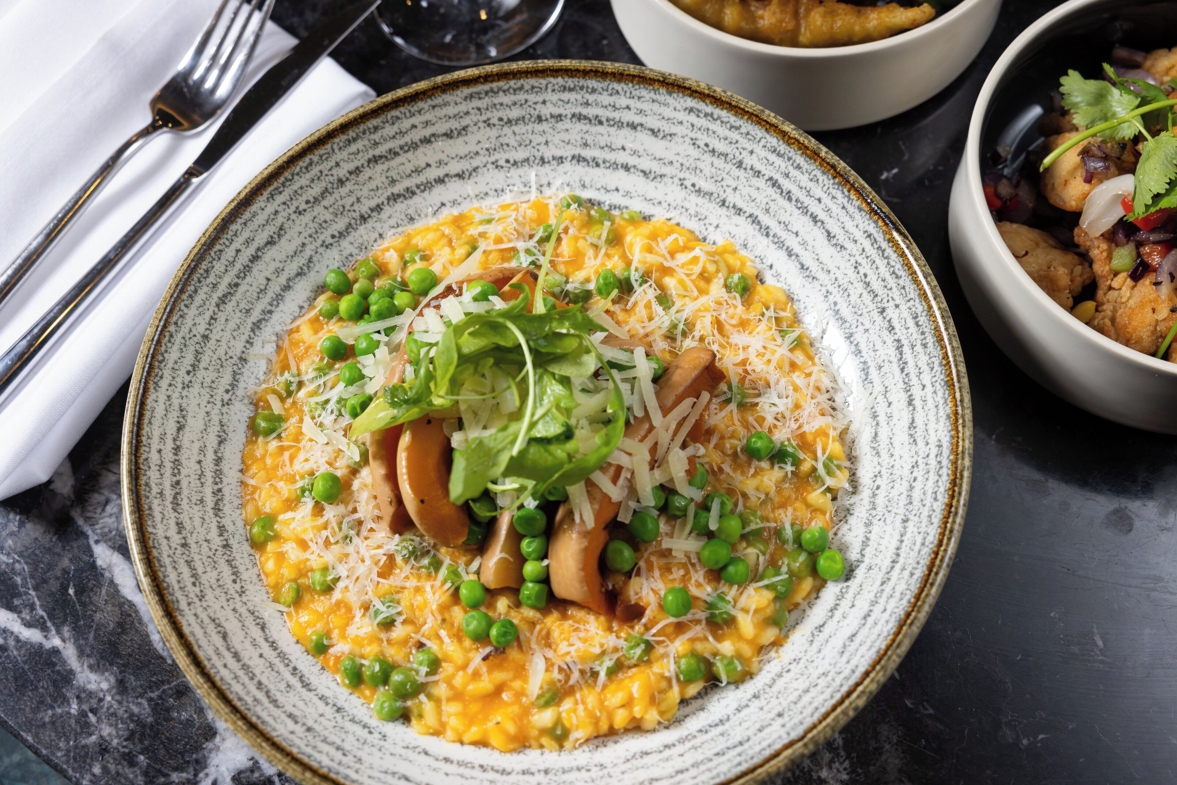 A plate of food with peas, cheese, and greens on a speckled ceramic plate.