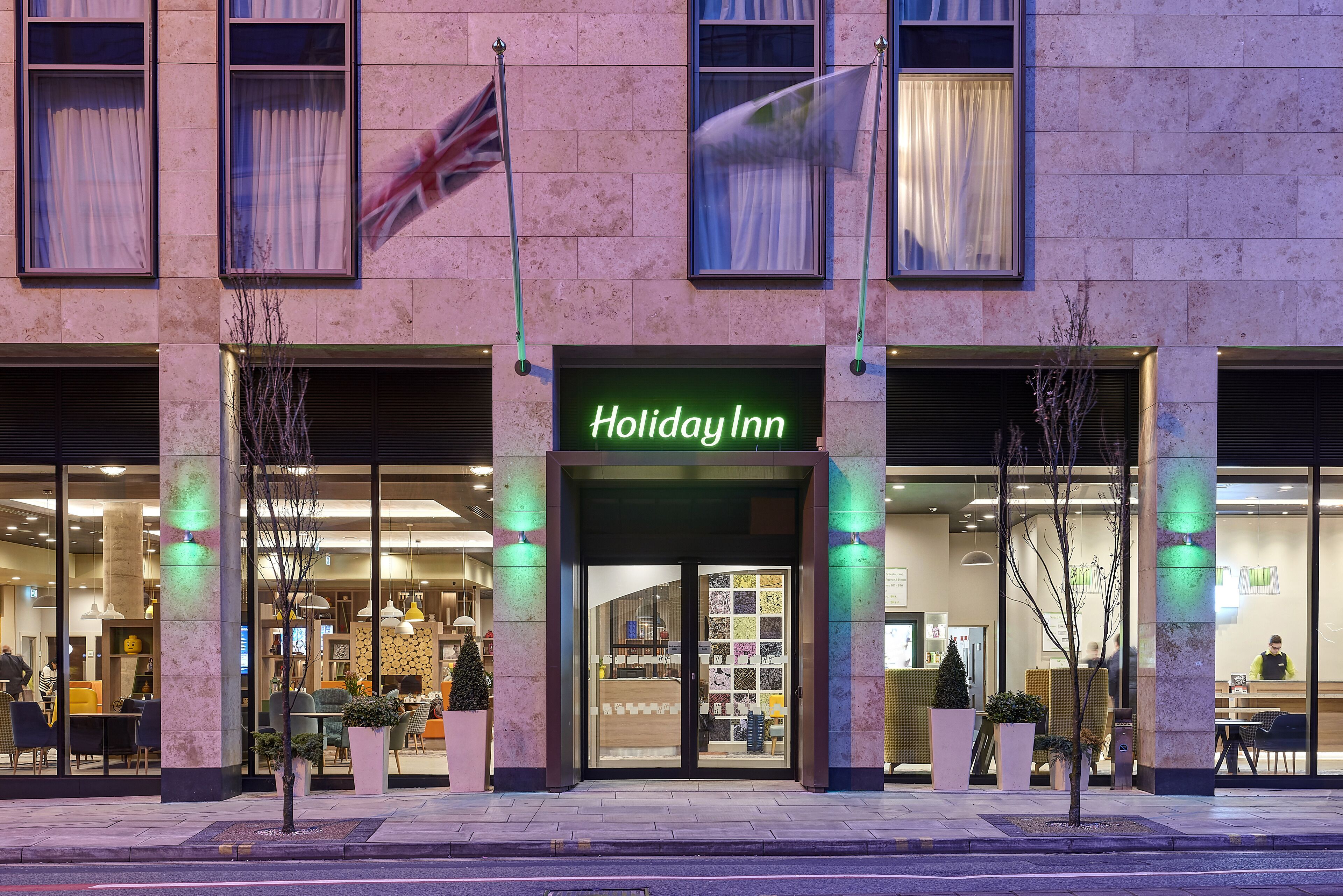 Un hôtel Holiday Inn doté d’une façade moderne, de grandes fenêtres et d’une entrée bien éclairée.