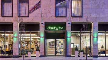 A Holiday Inn hotel with a modern facade, large windows, and a well-lit entrance.