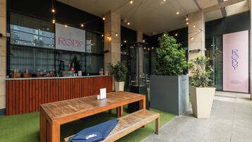 A modern bar area with a wooden counter, seating, and potted plants.