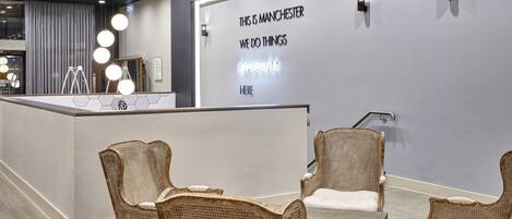 A reception area with a modern design, featuring a reception desk, wicker chairs, and a wall with a motivational quote.