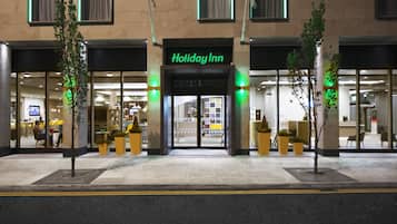 El exterior de un hotel Holiday Inn con una fachada moderna, grandes ventanales y una entrada destacada.