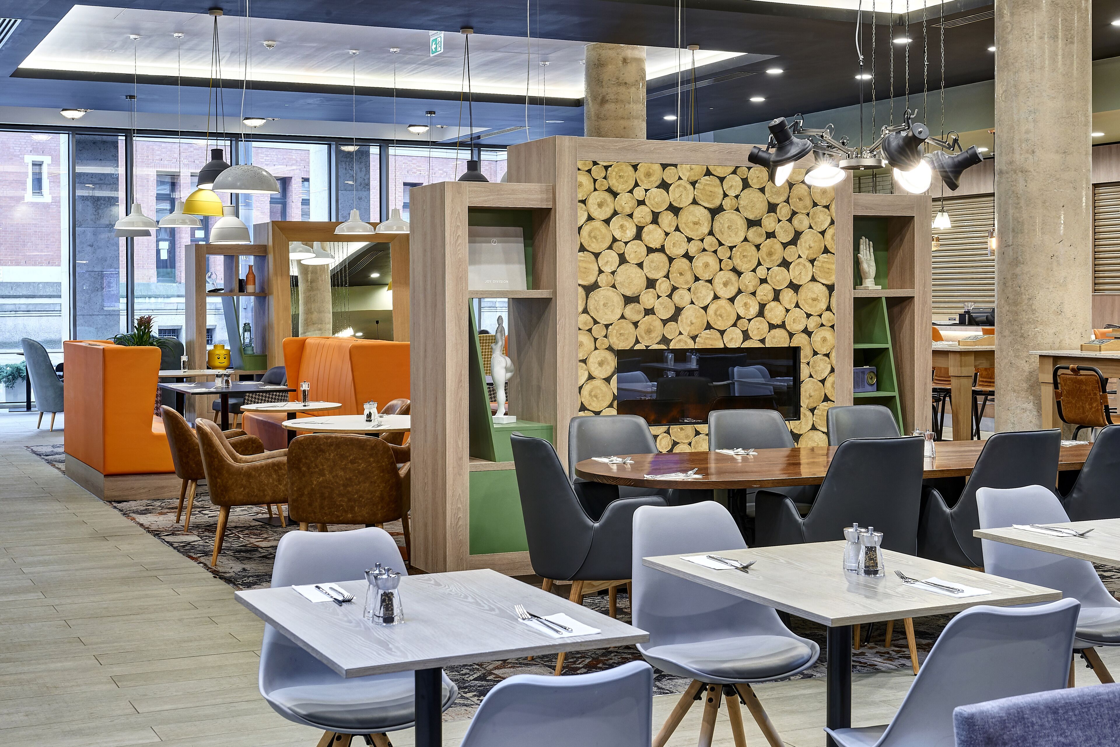 A modern restaurant with round tables and chairs, a wooden wall with a log pattern, and pendant lighting.