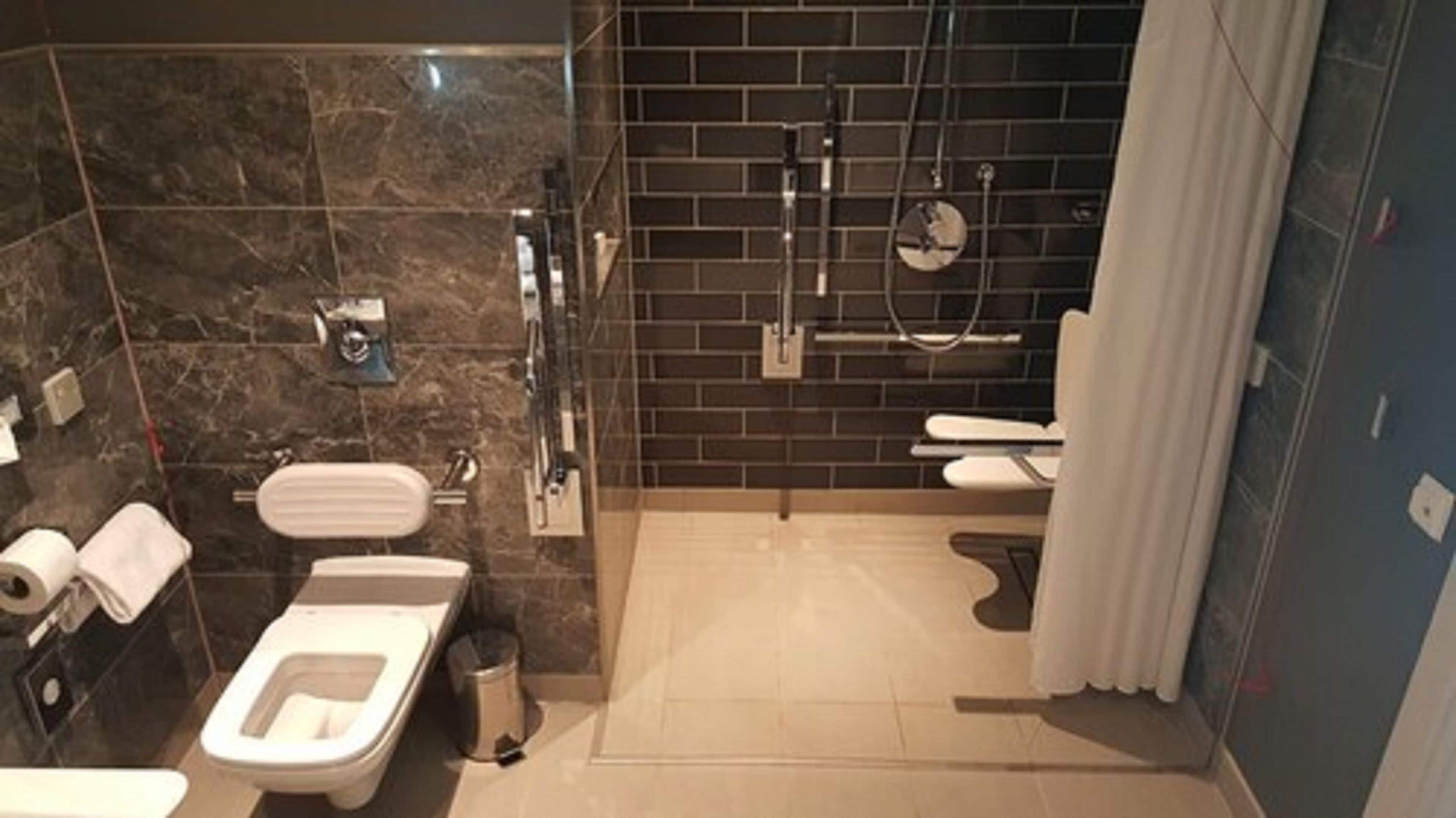 A modern bathroom with a toilet, bidet, and shower area.