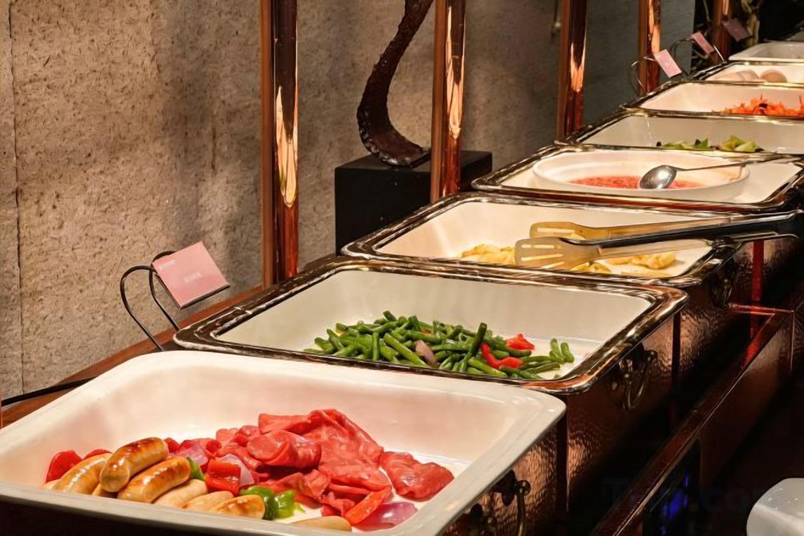 A buffet with various food options including meats, vegetables, and salads.