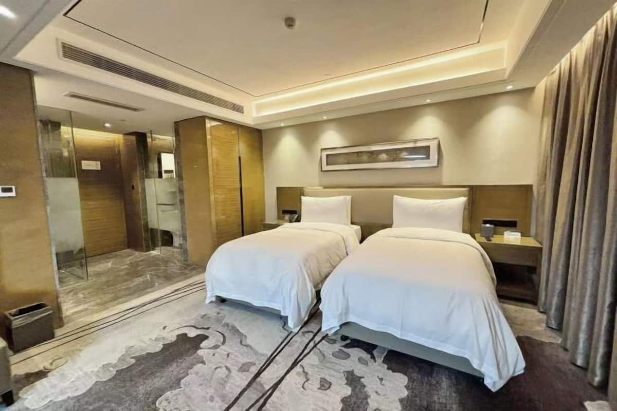 A hotel room with two beds, a large mirror, a framed picture on the wall, and a carpeted floor.
