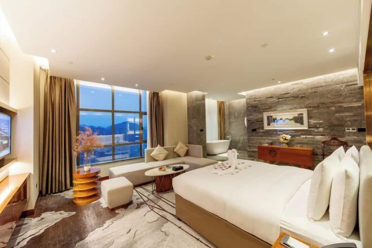 A modern hotel room with a large bed, a sofa, a small table, and a TV.